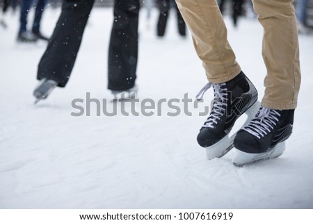Close up of skater legs at open skating rink, front view, place for text/ Mens black skates on white ice/ Weekend activities outdoor in cold weather/  