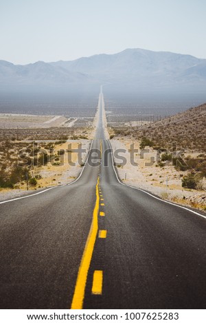 Classic panorama view of an endless straight road running through the barren scenery of the American Southwest with extreme heat haze on a beautiful sunny day with blue sky in summer Royalty-Free Stock Photo #1007625283