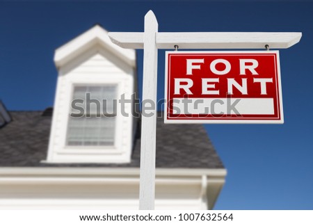 Right Facing For Rent Real Estate Sign In Front of House and Deep Blue Sky.