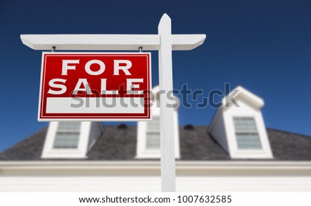 Left Facing For Sale Real Estate Sign In Front of House and Deep Blue Sky.