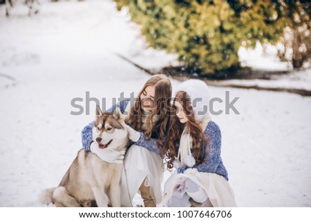 Two sisters in the park in the winter with a Husky dog.