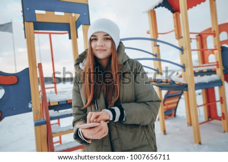 girl walking in a winter city and makes the photo on the playground