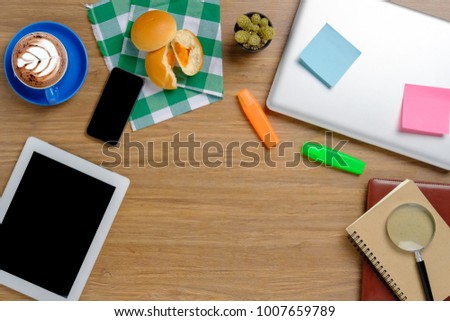 Office desktop with laptop,notepad,notebook,bakery,smartphone,tablet,calculator,headphone and cup of coffee.Top view with copyspace.