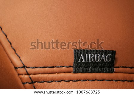 Word "Airbag" written on car's leather seat.