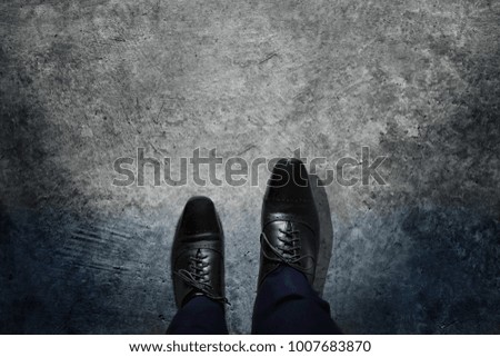 Success and Leadership Concept, Businessman with Black Oxford Shoes Walking from the Dark into the Light, Top View, Dark Cement Grunge as background