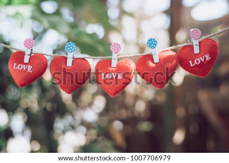 Red hearts hang  with a clothespin, natural background,Valentine's Day concept.
