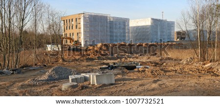 New mass production houses in the forest are built on clay and sand.  The construction site is the sunset of the winter  January day. Panoramic collage from several outdoor photos