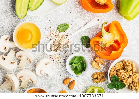 Ingredients for healthy seasonal food of green, orange and white flowers: cucumber, zucchini, mushrooms, dried apricots, sweet peppers, oranges, quinoa, almonds, walnut, mint, frisee. Copy space