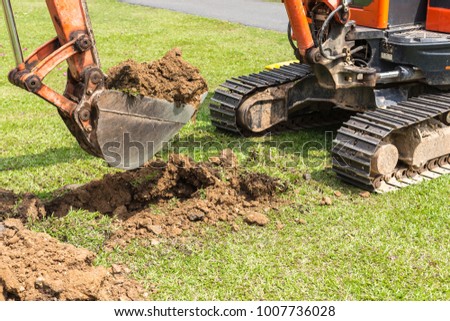 Excavator machine operate for digging soil and repair road in the public park Royalty-Free Stock Photo #1007736028