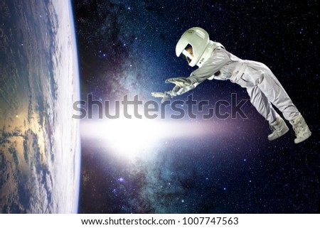 Astronaut in space, in zero gravity near the planet Earth. The concept is to find a new earth. Elements of this image furnished by NASA. Royalty-Free Stock Photo #1007747563