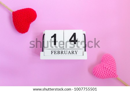Top view of wooden calendar 14 february with red heart and pink heart on pink background,this image for valentine day concept.