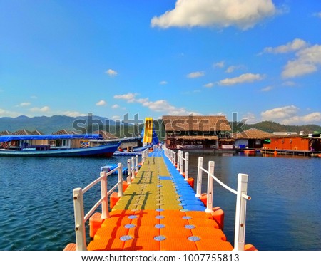 The walkway of the plastic floating bridge with a boat nearby. Lake Heaven Resort & Park, Kanchanaburi, Thailand Royalty-Free Stock Photo #1007755813