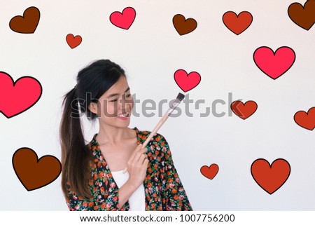 Valentines Day, love and art concept- Headshot portrait of a young asian cute woman holding paint brush smiling with red heart illustration doodle icon at the back ground