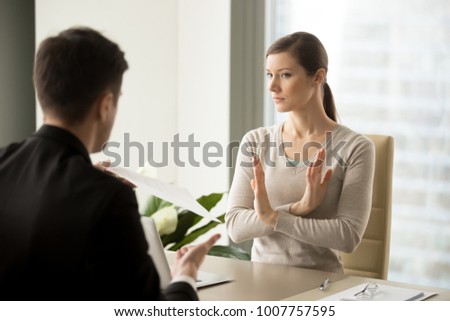 Unconvinced in honesty of business agreement female entrepreneur refusing to sign contact with businessman. Skeptical young woman rejecting job offer when sitting at desk in front of hiring manager Royalty-Free Stock Photo #1007757595