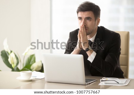 Worried company leader thinking about problem solution, pondering important question, frustrated because of difficulties in business while sitting at desk. Religious businessman praying at workplace Royalty-Free Stock Photo #1007757667