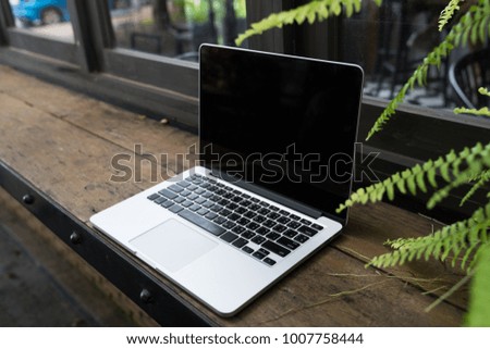 Laptop with blank screen on table, Coffee shop blurred background