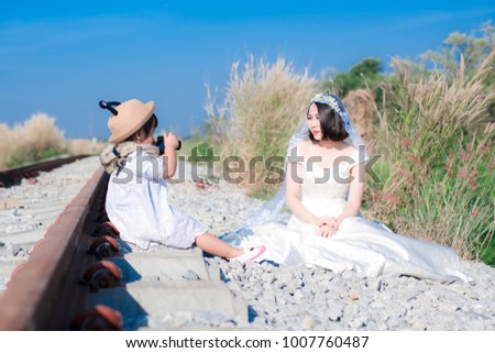 Girl holding a camera Bride Photo Railroad track in the morning blue sky