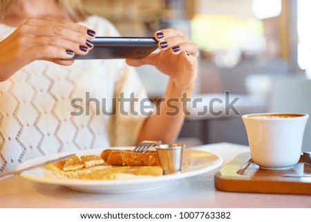 Closeup of women's hands taking photo of tasty breakfast on mobile phone camera.