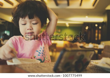asian  chinese child playing smartphone and eating. children watching cartoon. kid use phone
