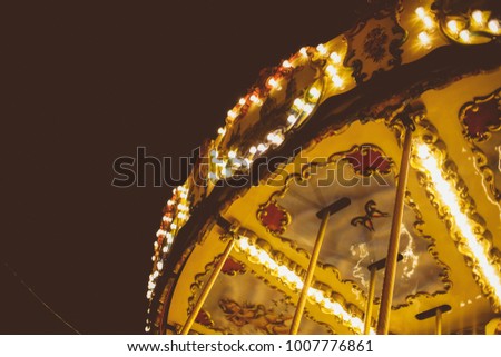 Children's Carousel at an amusement park in the evening and night illumination. amusement park at night. Outdoor vintage colorful carousel in the the city / carousel detail. Vintage photo processing