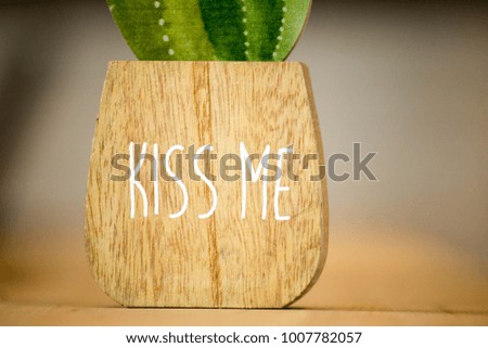 Succulent and purple flower in wooden pot on wooden table background with copy space kiss me text 
