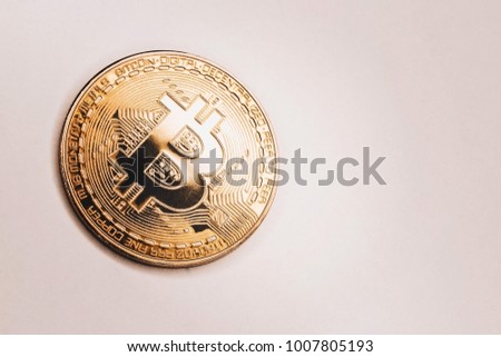 A large gold coin of crypto-currency bitcoin on a gentle pink background.