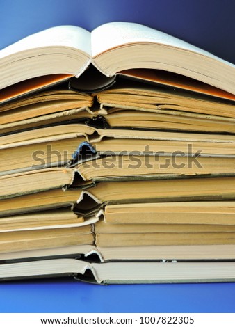 Stack of books background. Many books piles. Books lying on the table in the public library. Knowlege and education concept.Books in a firm cover lie one on one on a surface.Learning concept.Bookshelf