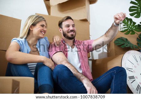 Young couple celebrating moving to new home sitting among boxes