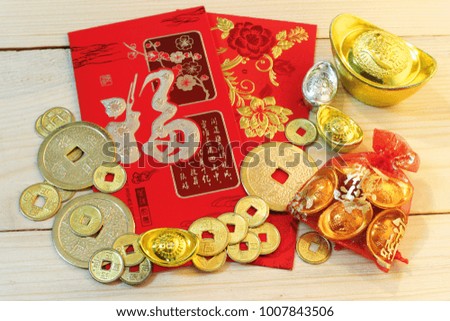 Gold and money coin on red pocket " Ang Pao" with background wood plate.Chinese text mean "Happy".