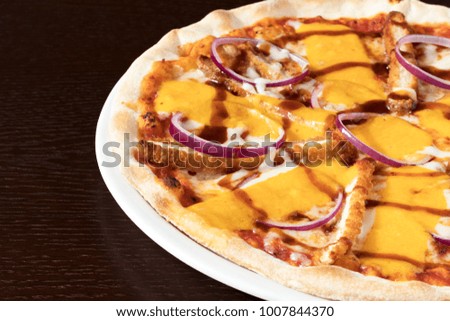 Breaded chicken Pizza with onions served on a white plate