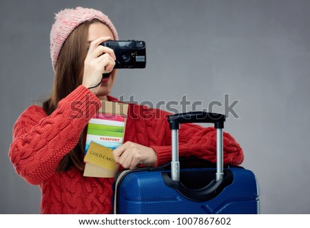 Woman dressed red sweater taking pictures with camera. Travel portrait concept.