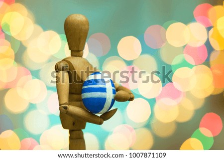 Easter Day , Closeup of a wooden puppet holding a Easter egg on bokeh background