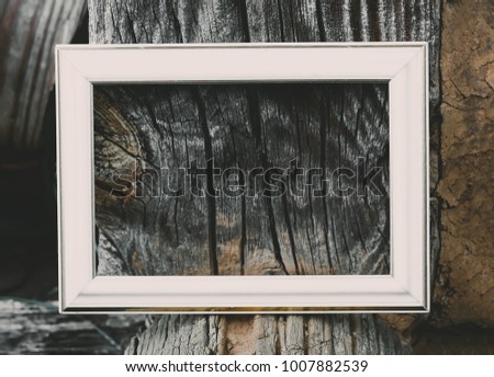 Empty picture or photo frame on weathered wood background.