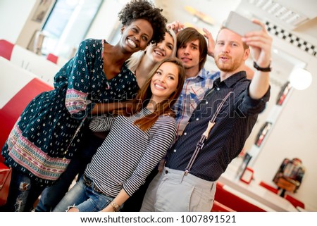 Group of happy young people taking selfie with mobile phone in the diner