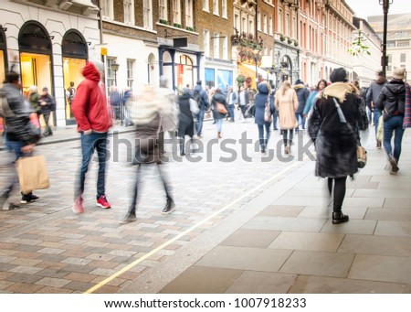 A busy high street with anonymous crowds of shoppers with shopping bags Royalty-Free Stock Photo #1007918233
