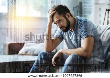 What I have to do. Sad exhausted unshaken man sitting in the bright room feeling bad himself and holding hand near head. Royalty-Free Stock Photo #1007927896