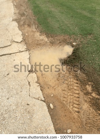 Side walk away path with hole full of water and mud because its cracked.