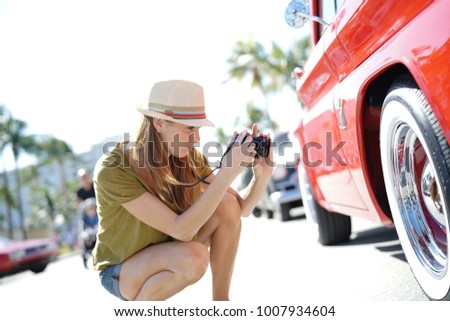 Woman photographer taking pictures of old-fashioned car