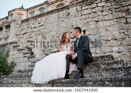 Romantic wedding couple sitting on the stairs next to the castle.