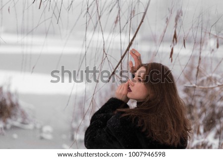 The girl in a mink coat in a snowy forest.