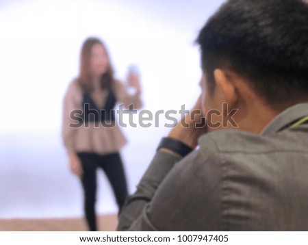 Back of Photographer shooting woman model in equipped studio, blurry background