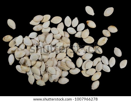 Shelled pumpkin seeds isolated on black background, top view