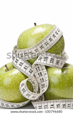 Measuring tape wrapped around a green apple as a symbol of diet.