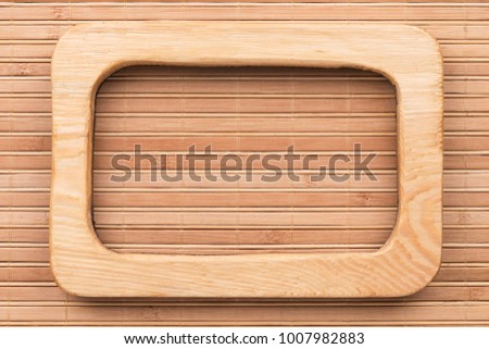 Beautiful one-piece light wooden frame, lies on bamboo mat. Natural patterns, texture