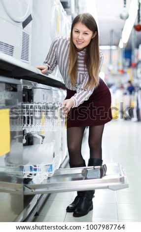 Positive girl looking for functional dish washer in section of consumer electronics
