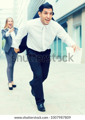 Manager is running away from angry woman boss outdoors.