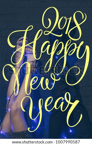 cropped shot of couple with christmas lights on legs, with "2018 happy new year" lettering