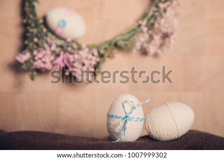 Easter still life background with Easter eggs and flower wreath, pastel colours decoration from rope, ribbon with wooden background