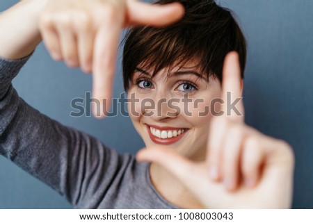 Attractive woman with a lovely smile making a frame gesture with her fingers framing her face