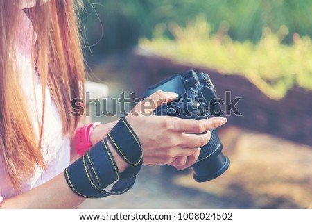 Photography and travel. Young woman holding camera sitting outdoor excited review her photographic performance. Young traveler using digital camera taking a picture for a good memory while travelling.